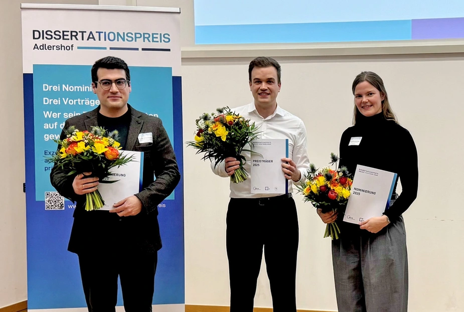3 Personen mit Urkunden und Blumensträußen